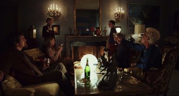 Movie still from “Knives Out” (2019), directed by Rian Johnson – A group of people sitting around a living room drinking wine; Wide shot, Low angle