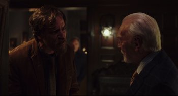 Movie still from “Knives Out” (2019), directed by Rian Johnson – Two men are talking in a dark room; Medium shot, Over the shoulder angle
