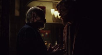 Movie still from “Knives Out” (2019), directed by Rian Johnson – Two men are talking in a dark room; Medium shot, Over the shoulder angle