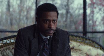 Movie still from “Knives Out” (2019), directed by Rian Johnson – A man wearing a suit and tie sitting in front of a window; Close Up shot, Over the shoulder angle