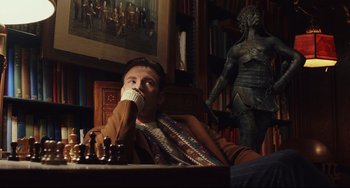 Movie still from “Knives Out” (2019), directed by Rian Johnson – A man sitting in front of a chess board drinking from a mug; Medium shot, Low angle