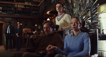 Movie still from “Knives Out” (2019), directed by Rian Johnson – A man and a woman sitting next to a man holding a remote; Medium shot, Low angle