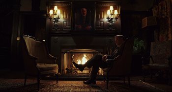 Movie still from “Knives Out” (2019), directed by Rian Johnson – A man sitting in front of a fire place; Wide shot, Low angle