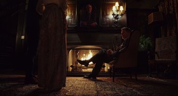 Movie still from “Knives Out” (2019), directed by Rian Johnson – A man sitting in front of a fire place; Wide shot, Low angle
