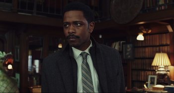 Movie still from “Knives Out” (2019), directed by Rian Johnson – A man wearing a suit and tie standing in a room; Medium shot, Over the shoulder angle