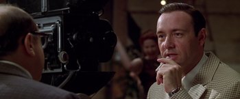 Movie still from “L.A. Confidential” (1997), directed by Curtis Hanson – A man standing in front of a video camera; Close Up shot, Over the shoulder angle