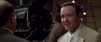 Movie still from “L.A. Confidential” (1997), directed by Curtis Hanson – A person with a movie camera; Close Up shot, Over the shoulder angle