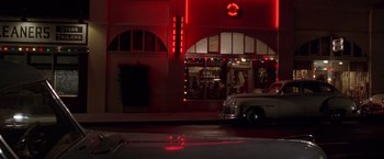 Movie still from “L.A. Confidential” (1997), directed by Curtis Hanson – A car parked in front of a building at night; Extreme Wide shot, Low angle