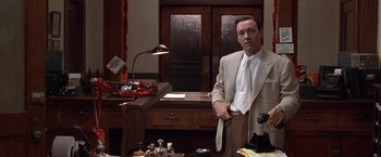 Movie still from “L.A. Confidential” (1997), directed by Curtis Hanson – A man in a suit standing in front of a desk; Medium shot, High angle