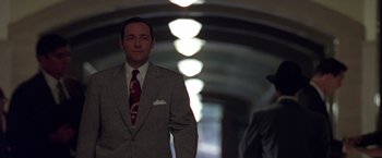 Movie still from “L.A. Confidential” (1997), directed by Curtis Hanson – A man in a suit and tie standing in front of another man in a suit and tie; Medium shot, Low angle