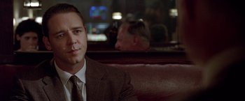 Movie still from “L.A. Confidential” (1997), directed by Curtis Hanson – A man in a suit and tie sitting in a restaurant booth; Close Up shot, Over the shoulder angle
