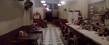 Movie still from “L.A. Confidential” (1997), directed by Curtis Hanson – An old fashioned diner has a checkerboard floor; Wide shot, High angle