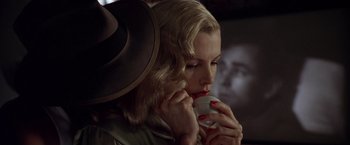 Movie still from “L.A. Confidential” (1997), directed by Curtis Hanson – A woman in a hat is talking on a cell phone; Close Up shot, Over the shoulder angle