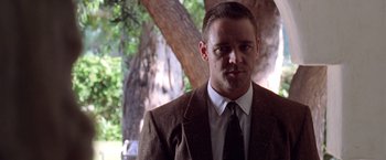 Movie still from “L.A. Confidential” (1997), directed by Curtis Hanson – A man wearing a suit and tie standing next to a tree; Close Up shot, Low angle