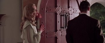 Movie still from “L.A. Confidential” (1997), directed by Curtis Hanson – A woman standing in front of a door and looking up; Medium shot, Low angle