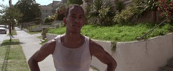 Movie still from “L.A. Confidential” (1997), directed by Curtis Hanson – A man in a white tank top standing in front of a building; Close Up shot, Low angle