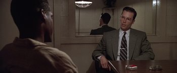 Movie still from “L.A. Confidential” (1997), directed by Curtis Hanson – A man sitting at a table in front of a mirror in front of another man; Close Up shot, Over the shoulder angle