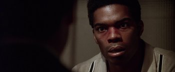 Movie still from “L.A. Confidential” (1997), directed by Curtis Hanson – A person with bruises on their face; Close Up shot, Over the shoulder angle