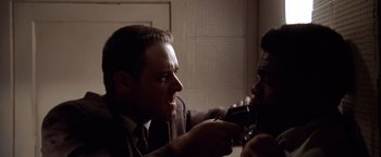 Movie still from “L.A. Confidential” (1997), directed by Curtis Hanson – A man in a suit and tie is shaving another man's beard; Close Up shot, High angle