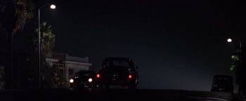 Movie still from “L.A. Confidential” (1997), directed by Curtis Hanson – A couple of cars driving down a street at night; Extreme Wide shot, Low angle