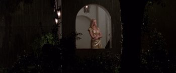 Movie still from “L.A. Confidential” (1997), directed by Curtis Hanson – A woman in a gold dress standing in front of an arched window; Wide shot, Low angle