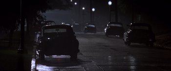 Movie still from “L.A. Confidential” (1997), directed by Curtis Hanson – Cars are parked on the side of the road at night; Wide shot, Low angle