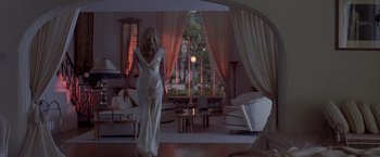 Movie still from “L.A. Confidential” (1997), directed by Curtis Hanson – A woman in a white dress in a living room; Wide shot, Low angle