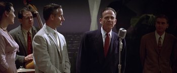 Movie still from “L.A. Confidential” (1997), directed by Curtis Hanson – A man in a suit and tie standing next to another man in a suit and tie; Medium shot, Low angle