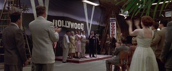 Movie still from “L.A. Confidential” (1997), directed by Curtis Hanson – A group of people standing on a stage with microphones; Wide shot, High angle