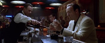 Movie still from “L.A. Confidential” (1997), directed by Curtis Hanson – A group of people sitting at a bar drinking wine; Medium shot, Low angle