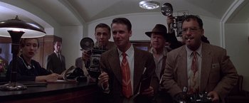 Movie still from “L.A. Confidential” (1997), directed by Curtis Hanson – A group of men standing next to each other in a room; Medium shot, Low angle