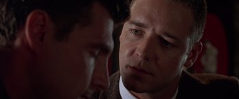 Movie still from “L.A. Confidential” (1997), directed by Curtis Hanson – A man looking at another man in a brown suit; Close Up shot, Over the shoulder angle