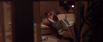 Movie still from “L.A. Confidential” (1997), directed by Curtis Hanson – A man and a woman laying on a couch in a living room; Wide shot, High angle