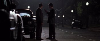 Movie still from “L.A. Confidential” (1997), directed by Curtis Hanson – A couple of men standing next to each other on a street; Wide shot, Over the shoulder angle