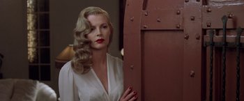 A beautiful blonde woman with red lipstick standing in front of a door