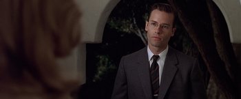 Movie still from “L.A. Confidential” (1997), directed by Curtis Hanson – A man in a suit and tie standing in front of an archway; Close Up shot, Low angle