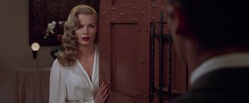 A woman in a white robe standing in front of a door