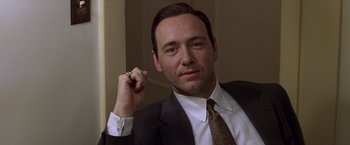 Movie still from “L.A. Confidential” (1997), directed by Curtis Hanson – A man in a suit and tie holding a pen; Close Up shot, Low angle