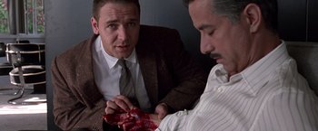 Movie still from “L.A. Confidential” (1997), directed by Curtis Hanson – Two men in suits looking at a piece of cloth; Medium shot, High angle