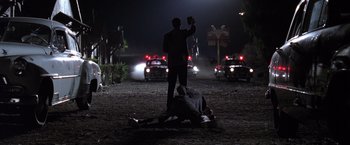 Movie still from “L.A. Confidential” (1997), directed by Curtis Hanson – A man standing over a dead body in the dark; Wide shot, Low angle