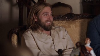 Movie still from “Don't Worry, He Won't Get Far on Foot” (2018), directed by Gus Van Sant – A man sitting on a couch with long blond hair; Medium shot, Over the shoulder angle