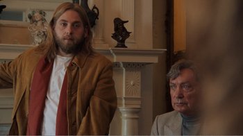 Movie still from “Don't Worry, He Won't Get Far on Foot” (2018), directed by Gus Van Sant – A man standing next to another man in front of a fireplace; Medium shot, Over the shoulder angle