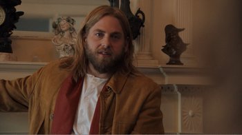 Movie still from “Don't Worry, He Won't Get Far on Foot” (2018), directed by Gus Van Sant – A man with long hair and a beard wearing a brown jacket; Medium shot, Over the shoulder angle