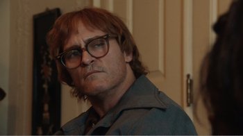 Movie still from “Don't Worry, He Won't Get Far on Foot” (2018), directed by Gus Van Sant – A person wearing glasses and a jacket; Close Up shot, Over the shoulder angle