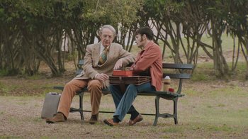 Movie still from “Don't Worry, He Won't Get Far on Foot” (2018), directed by Gus Van Sant – Two men sitting on a park bench talking to each other; Medium shot, Over the shoulder angle