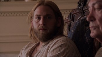 Movie still from “Don't Worry, He Won't Get Far on Foot” (2018), directed by Gus Van Sant – A man with long blonde hair sitting in front of a wall; Close Up shot, Over the shoulder angle