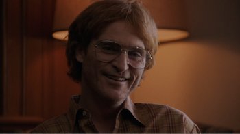 Movie still from “Don't Worry, He Won't Get Far on Foot” (2018), directed by Gus Van Sant – A person wearing glasses and smiling; Close Up shot, Over the shoulder angle