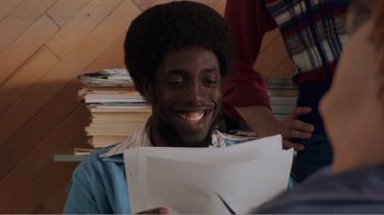 Movie still from “Don't Worry, He Won't Get Far on Foot” (2018), directed by Gus Van Sant – A man smiling while holding a piece of paper in front of him; Close Up shot, High angle