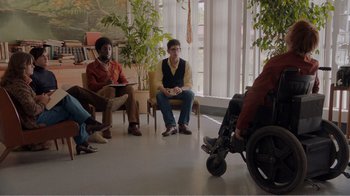 Movie still from “Don't Worry, He Won't Get Far on Foot” (2018), directed by Gus Van Sant – A group of people sitting in a room with plants; Wide shot, High angle