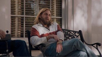 Movie still from “Don't Worry, He Won't Get Far on Foot” (2018), directed by Gus Van Sant – A man sitting on top of a wooden bench next to a window; Medium shot, Low angle